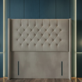 Gray tufted headboard against a blue paneled wall with two hanging lights.