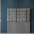 Gray tufted headboard against a marble wall with lighting accents
