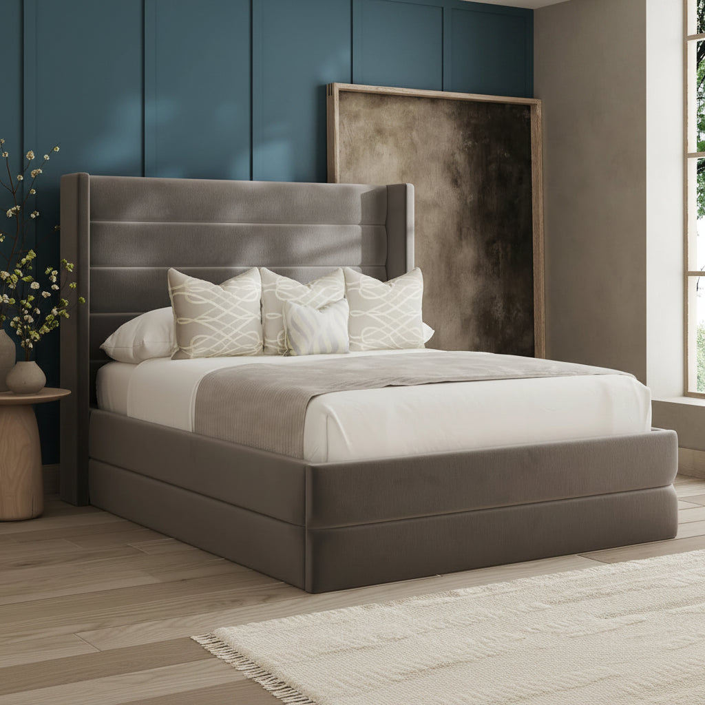 Gray upholstered bed with white bedding in a room with a window and side table.