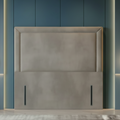Gray upholstered headboard against a blue paneled wall with pendant lights.