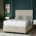 Neatly made bed with decorative pillows in a room with dark green walls and a lamp.