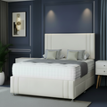 White upholstered bed with gray bedding in a bedroom setting.