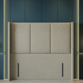 Beige upholstered headboard against a dark blue wall with pendant lights.