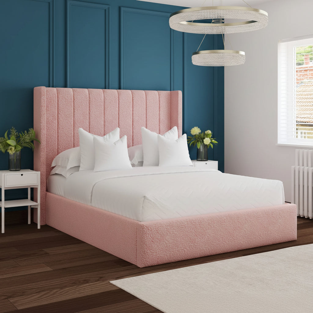 Pink upholstered bed in a modern bedroom with white walls and wooden flooring.