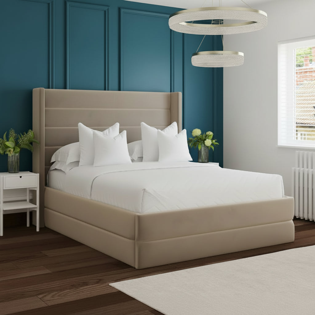 Beige upholstered bed in a modern bedroom with white walls and wooden flooring..